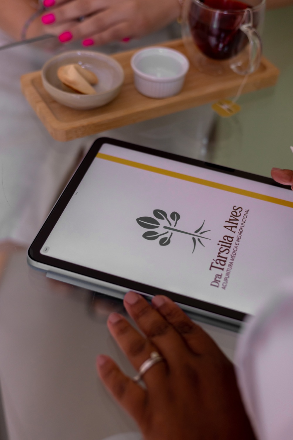 Tablet com a identidade visual da Dra. Társila Alves